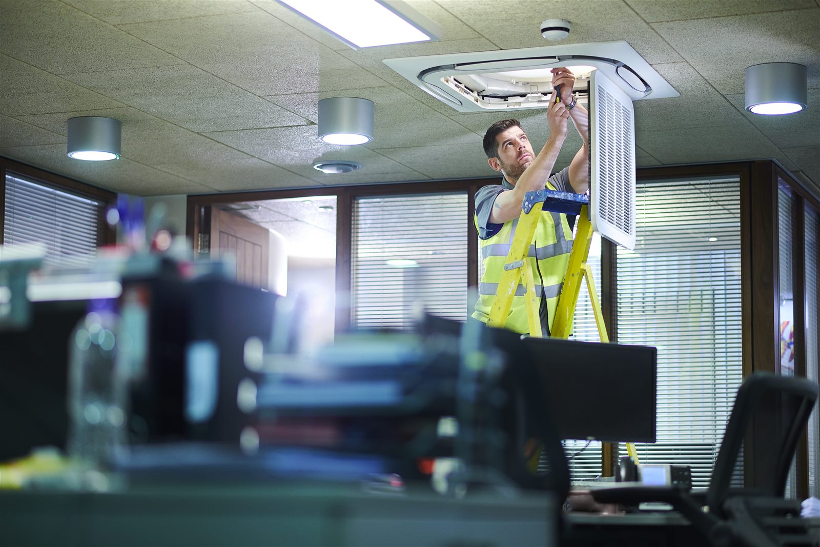 Technicien intervenant sur une climatisation dans des bureaux